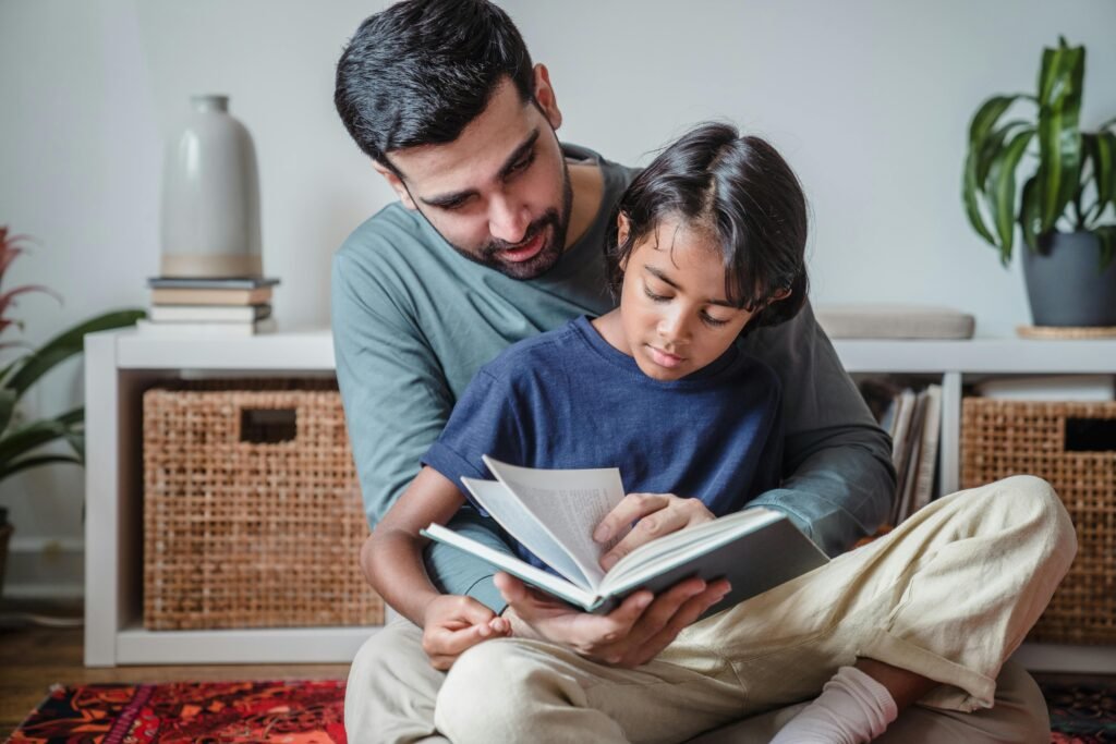 pexels-photo-9345612-9345612 A father reading a book with his son, enjoying quality time together indoors.